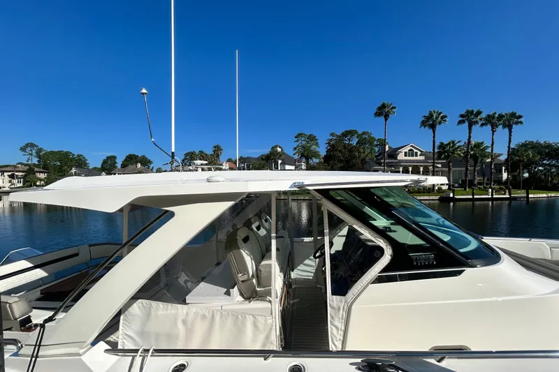  Yacht Photos Pics 2023 Tiara Yachts 38 LS on a serene waterfront with palm trees and blue sky.