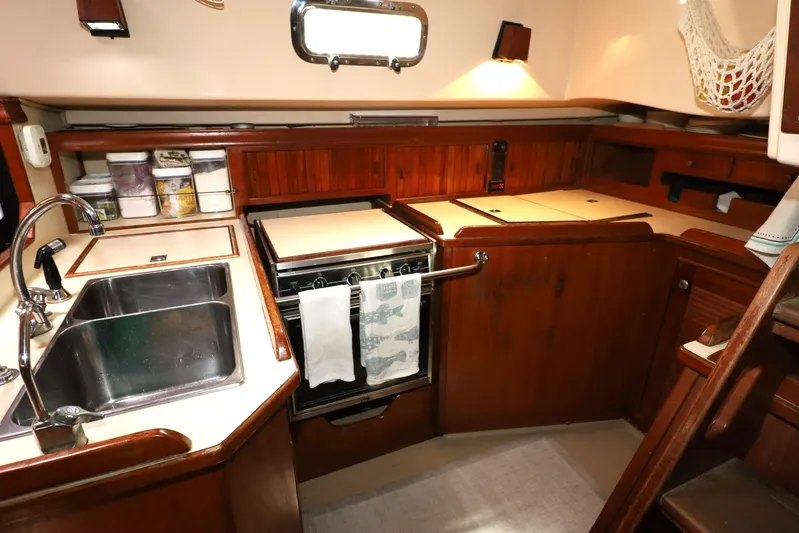 Carpe Diem Yacht Photos Pics Interior of 1995 Island Packet 40 sailboat kitchen with sink, stove, and wooden cabinetry.