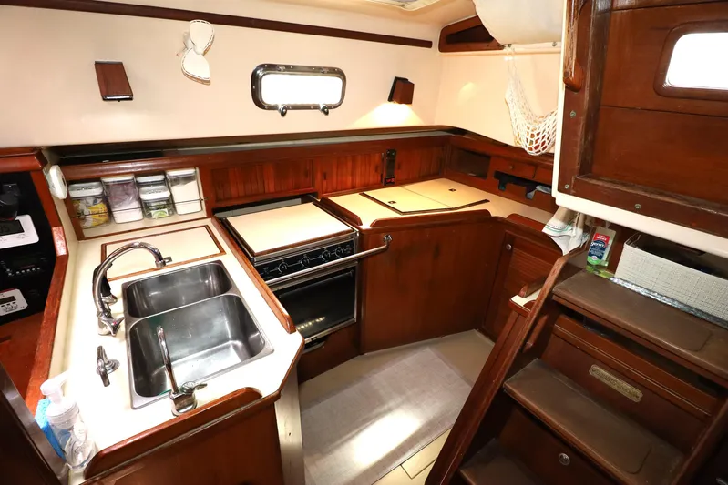 Carpe Diem Yacht Photos Pics 1995 Island Packet 40 yacht kitchen with dual sinks, stove, and wooden cabinetry.
