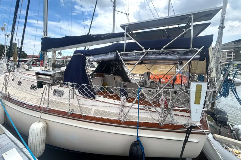 Carpe Diem Yacht Photos Pics 1995 Island Packet 40 sailboat docked at marina, featuring blue canopy and netted railings.