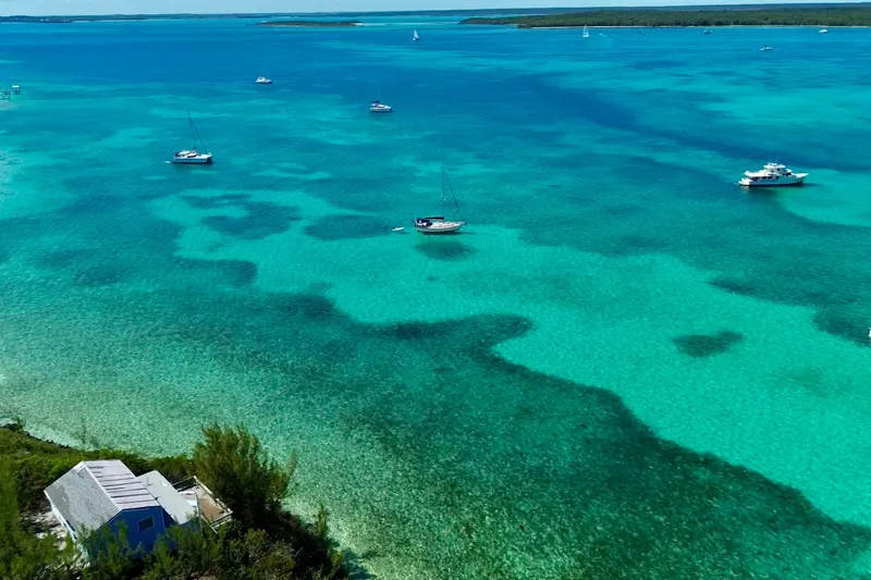 Carpe Diem Yacht Photos Pics Turquoise waters with sailboats, including a 1995 Island Packet 40, near a coastal house.