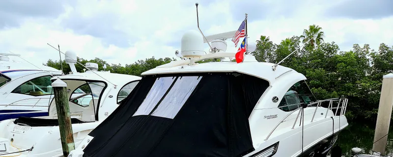 Moonwake Yacht Photos Pics 2014 Sea Ray 470 Sundancer yacht docked with flags, surrounded by greenery and other boats.