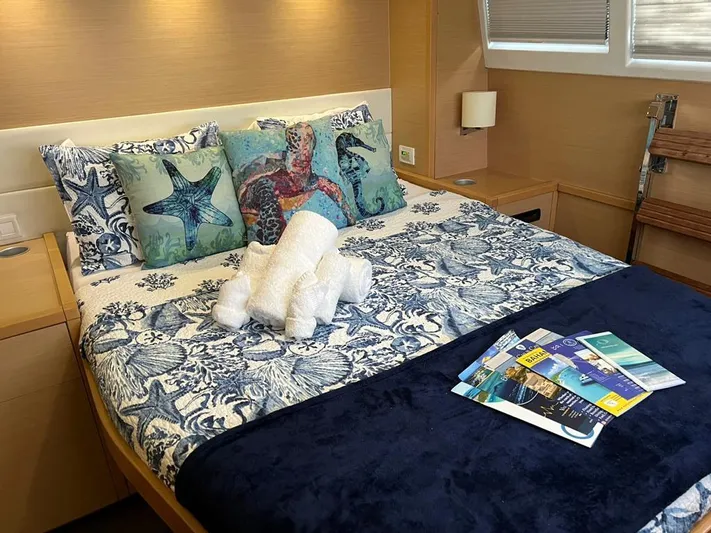 Tiger Lily Yacht Photos Pics Luxurious bedroom on 2015 Lagoon 620 yacht with nautical-themed decor and reading materials.