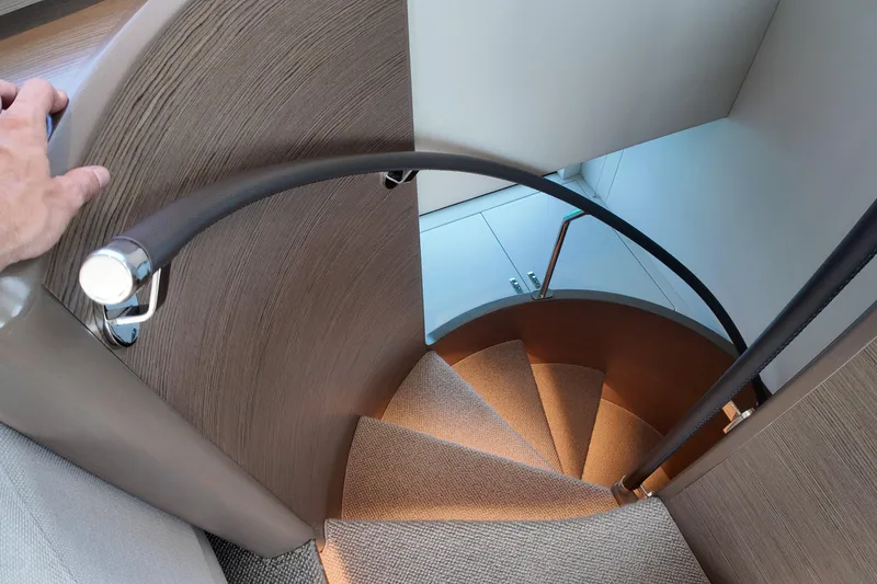 La Mer Yacht Photos Pics Spiral staircase inside 2023 Princess Y72 yacht, featuring elegant wood and metal design.