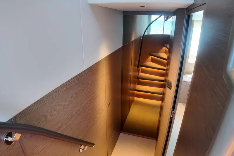 La Mer Yacht Photos Pics Luxurious interior staircase of 2023 Princess Y72 yacht, featuring elegant wood paneling and ambient lighting.