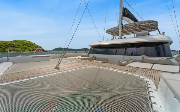 Ocean Vibes Yacht Photos Pics Luxury Sunreef 70 catamaran deck with netting, 2020 model, anchored near lush island.