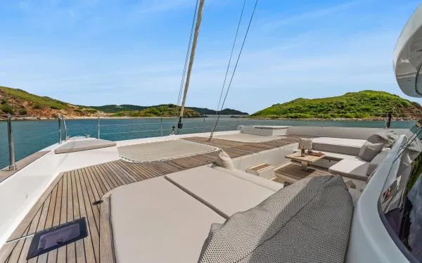 Ocean Vibes Yacht Photos Pics Luxurious Sunreef 70 yacht deck with elegant seating, surrounded by serene waters and lush green hills.