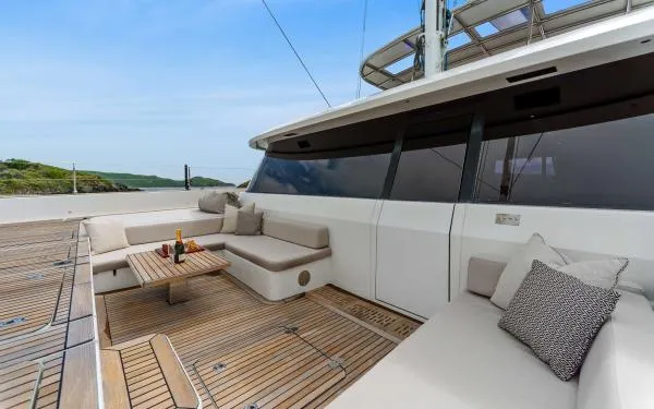 Ocean Vibes Yacht Photos Pics Luxurious Sunreef 70 yacht deck with elegant seating, wooden flooring, and scenic ocean view.
