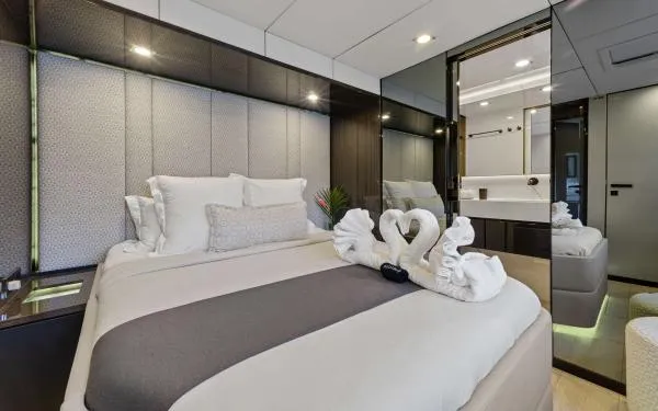 Ocean Vibes Yacht Photos Pics Luxurious bedroom interior on a 2020 Sunreef 70 yacht, featuring elegant decor and swan towel art.