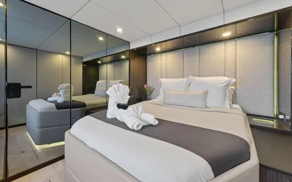 Ocean Vibes Yacht Photos Pics Luxurious bedroom interior on 2020 Sunreef 70 yacht with elegant bedding and mirrored walls.