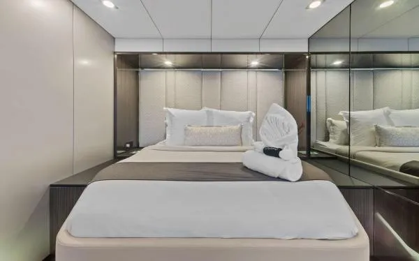 Ocean Vibes Yacht Photos Pics Luxurious bedroom interior on 2020 Sunreef 70 yacht, featuring elegant bedding and mirrored walls.