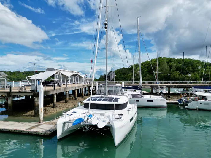Promprang Yacht Photos Pics 2020 Lagoon 50 catamaran docked in a marina under a partly cloudy sky.