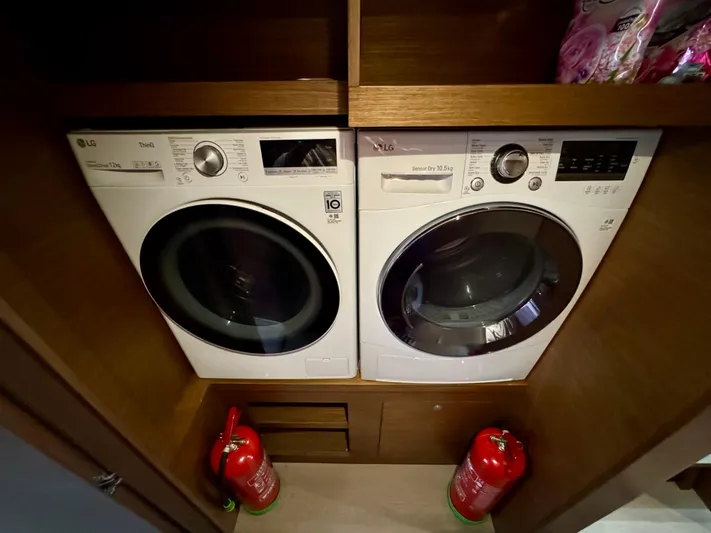 Promprang Yacht Photos Pics Laundry area with two front-loading washing machines and fire extinguishers on a Lagoon 50 yacht.