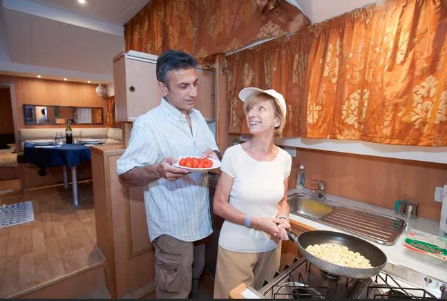 Houseboat Minuetto 6 Yacht Photos Pics Couple cooking in a 2009 Custom Minuetto 6 kitchen, preparing pasta and tomatoes.