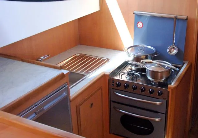 Houseboat Minuetto 6 Yacht Photos Pics Compact kitchen in a 2009 Custom Minuetto 6 boat with stove, sink, and countertop.