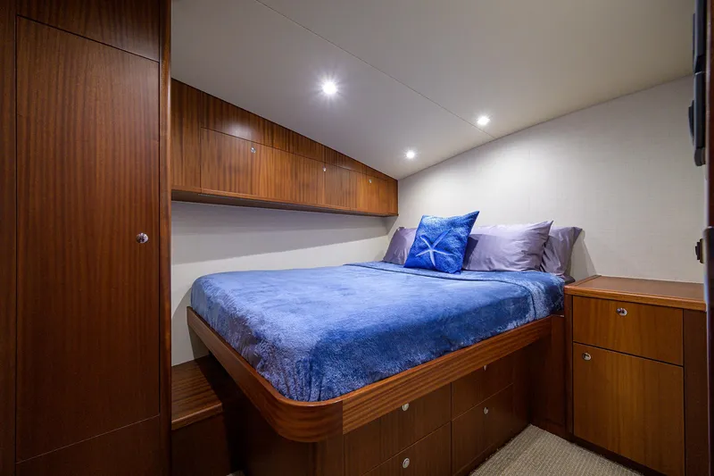  Yacht Photos Pics 2022 F&S 58 Custom Carolina yacht cabin with wooden cabinetry and blue bedding.