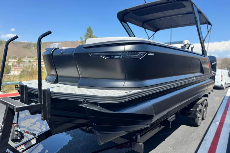  Yacht Photos Pics 2026 Manitou Explore Dual Engine boat on trailer, sleek black design, sunny day.