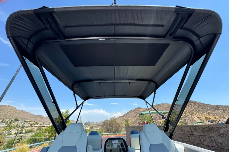  Yacht Photos Pics 2026 Manitou Explore Dual Engine boat with canopy, scenic mountain backdrop.