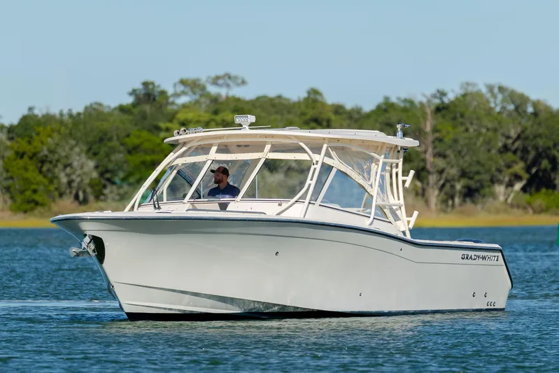  Yacht Photos Pics 2020 Grady-White Freedom 307 boat cruising on a serene lake with lush greenery.
