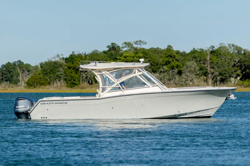  Yacht Photos Pics 2020 Grady-White Freedom 307 boat cruising on a calm lake with forested background.