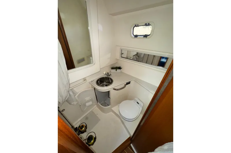 Island Oasis Yacht Photos Pics Compact bathroom in 2001 Cabo 35 Express boat with sink, toilet, and mirror.