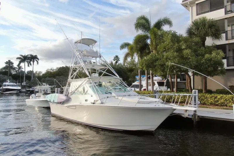 Island Oasis Yacht Photos Pics 2001 Cabo 35 Express yacht docked by palm trees and waterfront buildings.