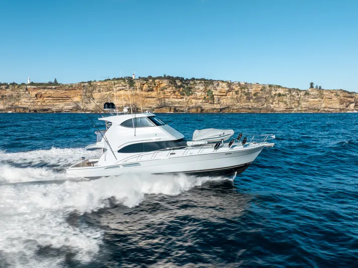 Riviera 61 Enclosed Flybridge Yacht Photos Pics 2011 Riviera 61 Enclosed Flybridge yacht cruising on blue ocean near rocky coastline.