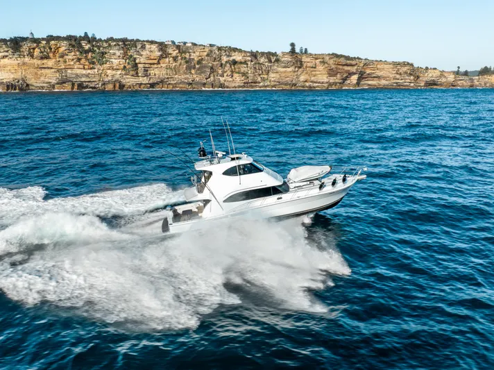 Riviera 61 Enclosed Flybridge Yacht Photos Pics 2011 Riviera 61 Enclosed Flybridge yacht cruising on open sea near rocky coastline.