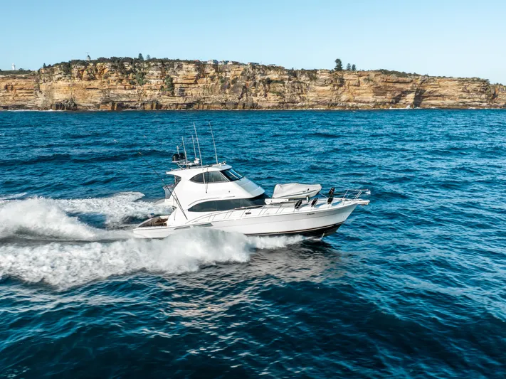 Riviera 61 Enclosed Flybridge Yacht Photos Pics Riviera 61 Enclosed Flybridge yacht cruising near rocky coastline, 2011 model.