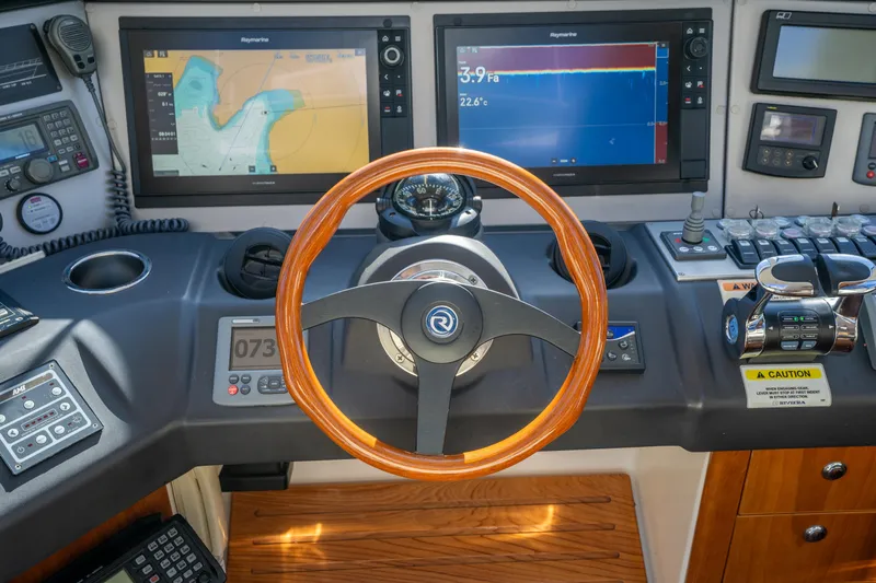 Riviera 61 Enclosed Flybridge Yacht Photos Pics Cockpit of 2011 Riviera 61 Enclosed Flybridge with navigation screens and wooden steering wheel.