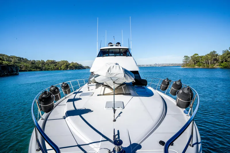 Riviera 61 Enclosed Flybridge Yacht Photos Pics 2011 Riviera 61 Enclosed Flybridge yacht on serene blue water, surrounded by lush greenery.