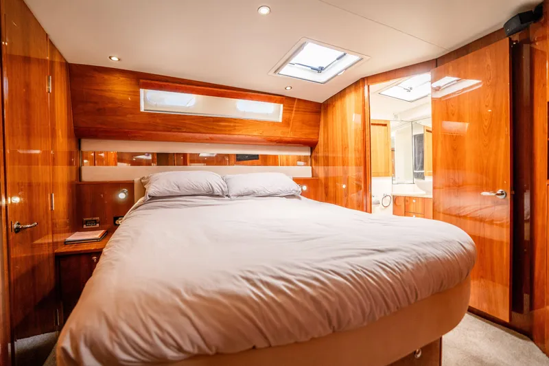 Riviera 61 Enclosed Flybridge Yacht Photos Pics Luxurious bedroom in 2011 Riviera 61 Enclosed Flybridge yacht with wood paneling and skylight.