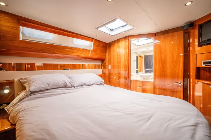 Riviera 61 Enclosed Flybridge Yacht Photos Pics Luxurious bedroom interior of 2011 Riviera 61 Enclosed Flybridge yacht with wood paneling.