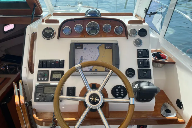 Tenacity Yacht Photos Pics Steering console of a 2012 Hunt Surfhunter boat with navigation equipment and wooden accents.