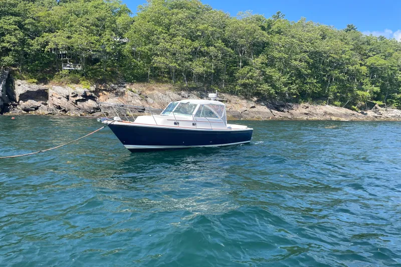 Tenacity Yacht Photos Pics 2012 Hunt Surfhunter boat anchored near rocky shoreline with lush greenery.
