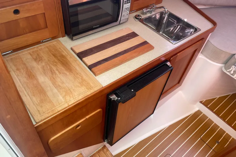 Tenacity Yacht Photos Pics Compact kitchen area in a 2012 Hunt Surfhunter boat with wooden cabinetry and appliances.