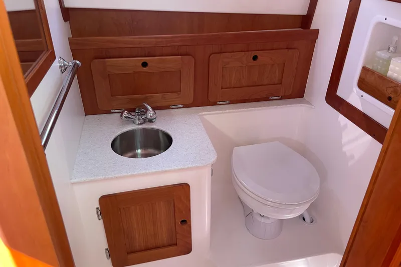 Tenacity Yacht Photos Pics Compact boat bathroom with sink and toilet, featuring wooden cabinetry. Hunt Surfhunter 2012 model.