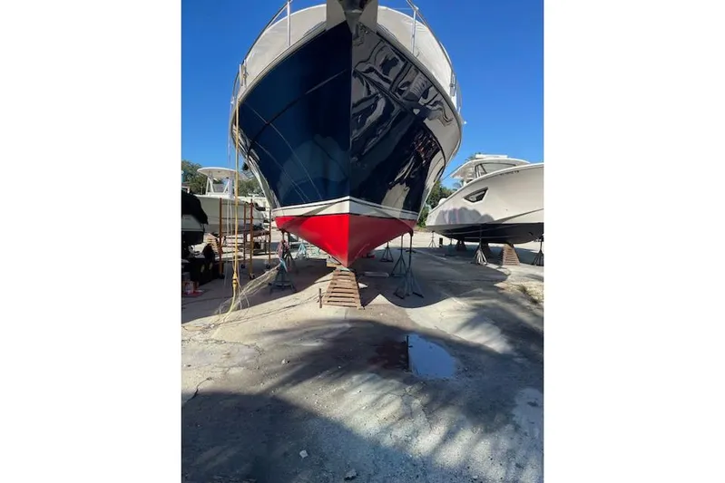 Perseus Yacht Photos Pics 2008 Mainship 34 Trawler Hardtop on dry dock, blue and red hull, sunny day.