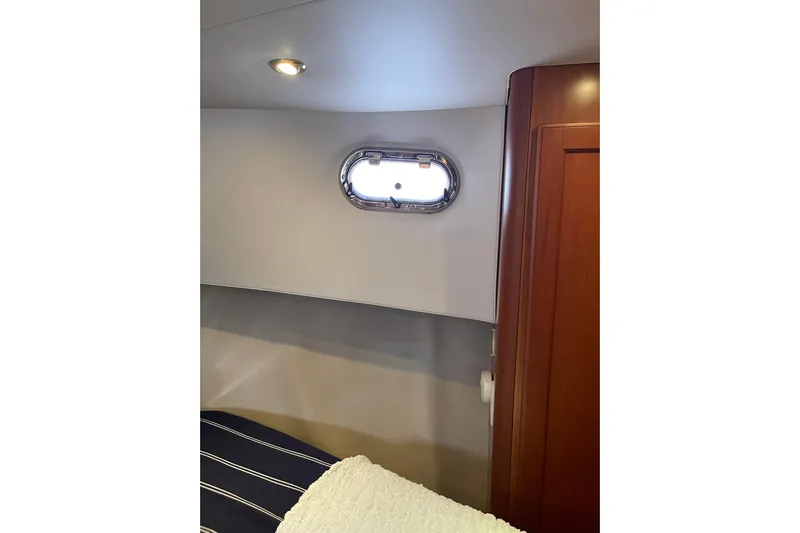 Perseus Yacht Photos Pics Interior cabin of 2008 Mainship 34 Trawler Hardtop with porthole and wooden accents.