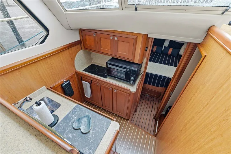 Perseus Yacht Photos Pics 2008 Mainship 34 Trawler Hardtop interior with kitchenette and cozy sleeping area.
