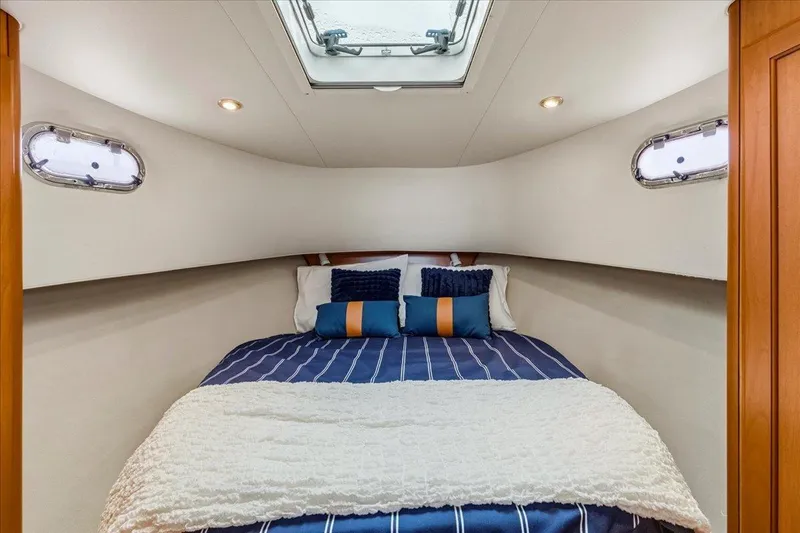 Perseus Yacht Photos Pics Cozy bedroom in 2008 Mainship 34 Trawler Hardtop with striped bedding and porthole windows.