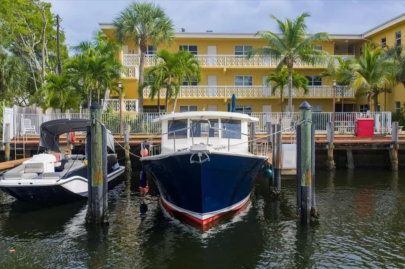 Perseus Yacht Photos Pics 2008 Mainship 34 Trawler Hardtop docked near yellow building with palm trees.