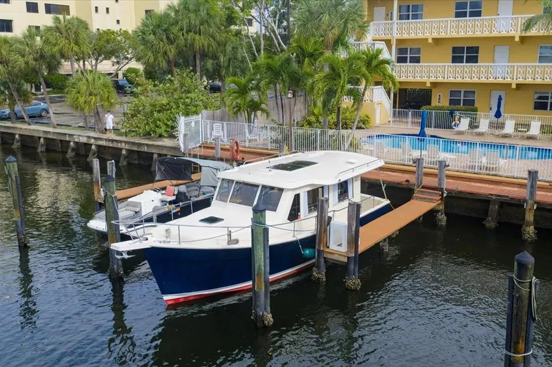 Perseus Yacht Photos Pics 2008 Mainship 34 Trawler Hardtop docked near a waterfront property with palm trees.