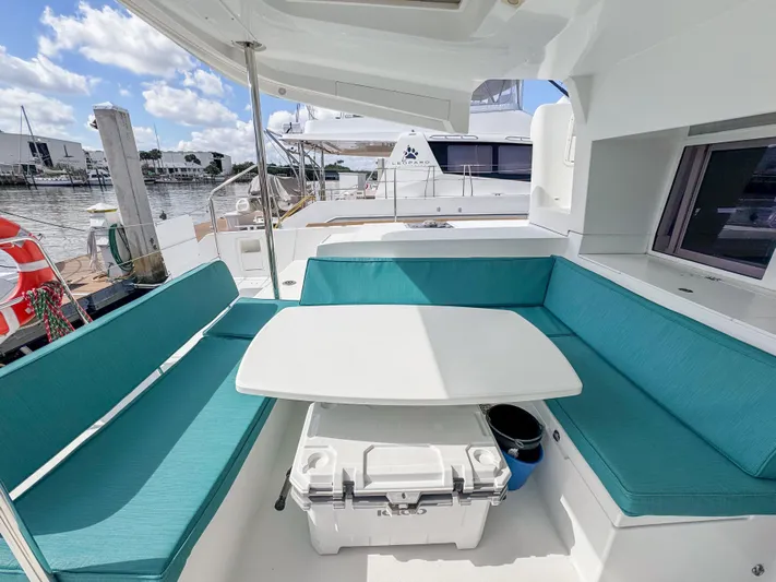 Sunshine Yacht Photos Pics Outdoor seating area on a 2017 Lagoon 450 F catamaran, featuring turquoise cushions and a white table.