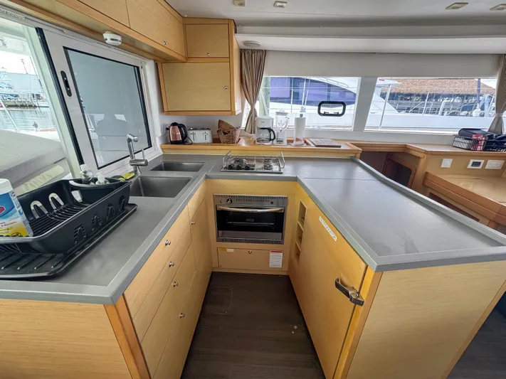 Sunshine Yacht Photos Pics Modern kitchen interior of 2017 Lagoon 450 F catamaran with wooden cabinetry and appliances.