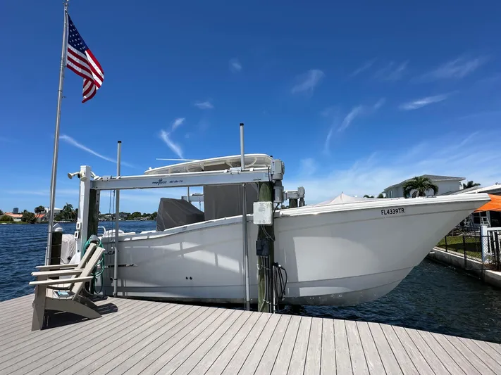  Yacht Photos Pics 2024 World Cat 280ccx boat docked, American flag, clear blue sky, waterfront view.