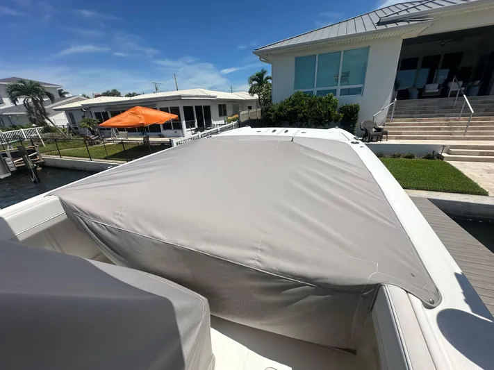  Yacht Photos Pics 2024 World Cat 280ccx boat with cover, docked near waterfront homes.