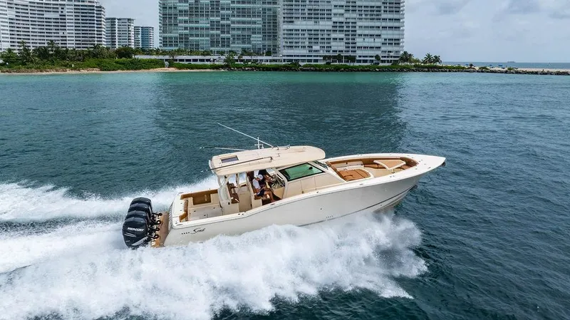  Yacht Photos Pics 2018 Scout 420 LXF boat cruising near coastal buildings on a sunny day.