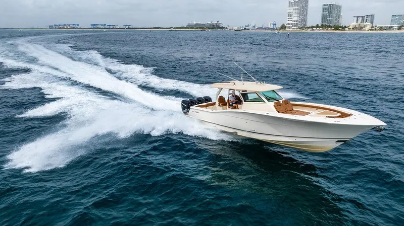  Yacht Photos Pics 2018 Scout 420 LXF boat cruising on open water near city skyline.