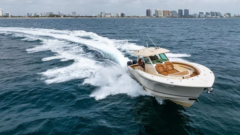  Yacht Photos Pics 2018 Scout 420 LXF boat cruising on ocean near city skyline.